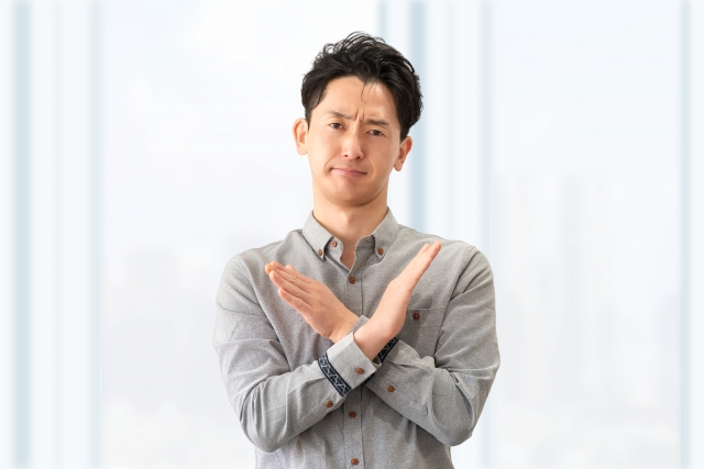 胸元でバツを作る男性