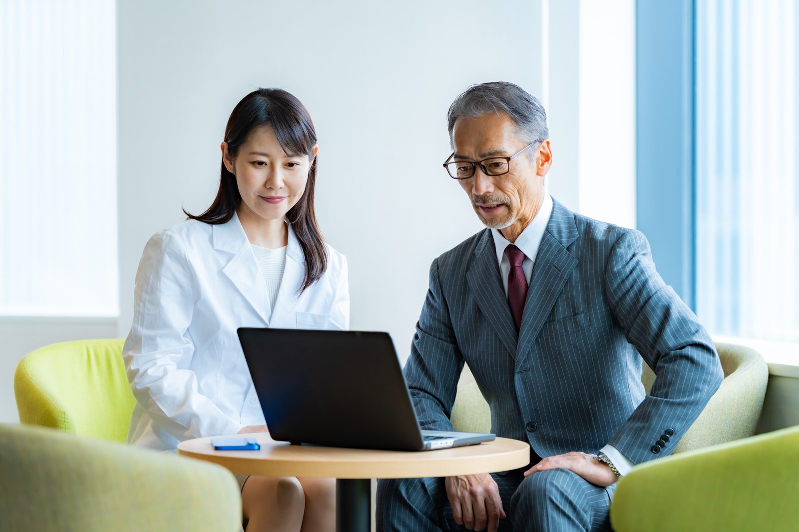 ノートパソコンを見ながら経営者と打ち合わせをする様子