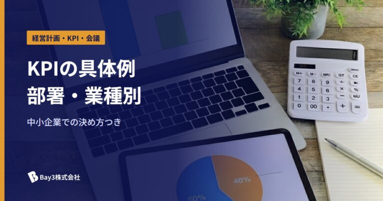 ノートパソコンと円グラフを映したタブレット、電卓が並ぶ机